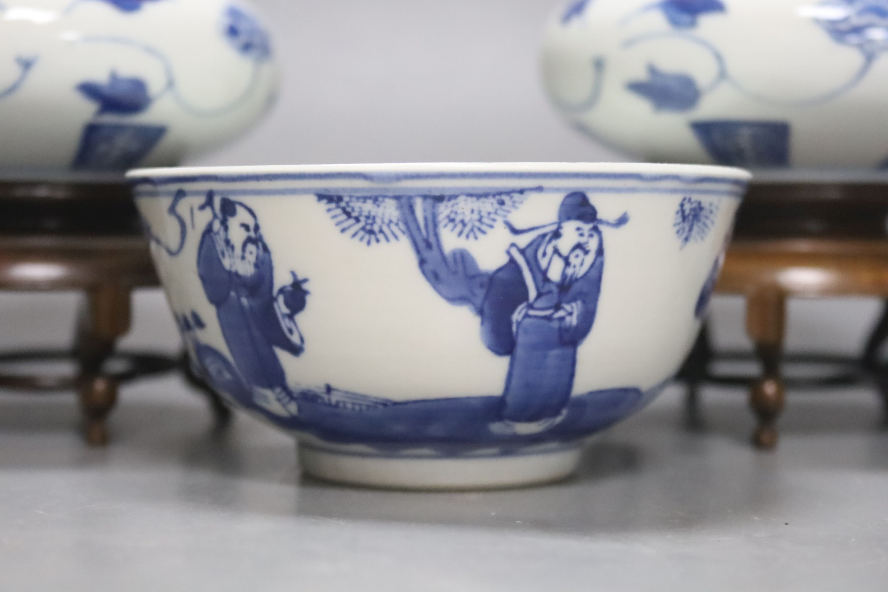 A pair of Chinese blue and white jars and covers, 6.5cm, on wood stands, a Chinese blue and white bowl and two small enamelled wine cups